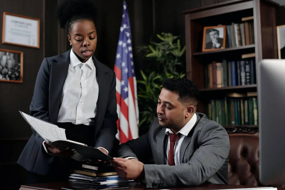 Black business woman reviewing documents with man sitting