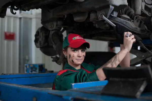 female mechanic with red hat working on car