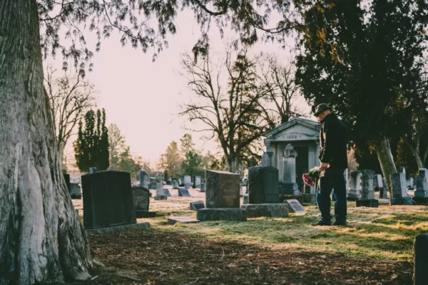 person alone in the cemetery during the day staring at grave
